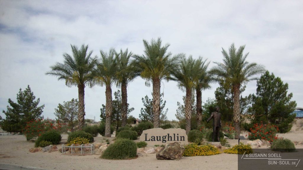 Ortseingang von Lauglin: Kleine Wüstenoase mit Palmen und Ortseingangsschild Laughlin