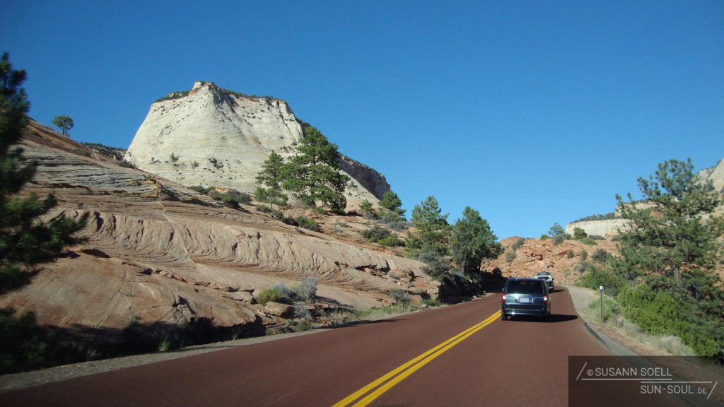 Die gigantischen Felsen und die rote Straße leuchten uns in der Sonne regelrecht den Weg.
