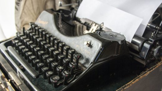 Alte Schreibmaschine, in die ein weißes Blatt Papier eingespannt ist